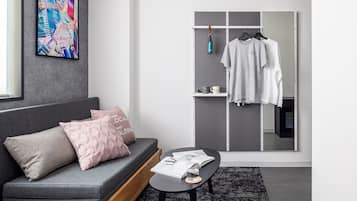 A modern room with a grey sofa, a small coffee table, a magazine, and a mirror with a hanging garment.