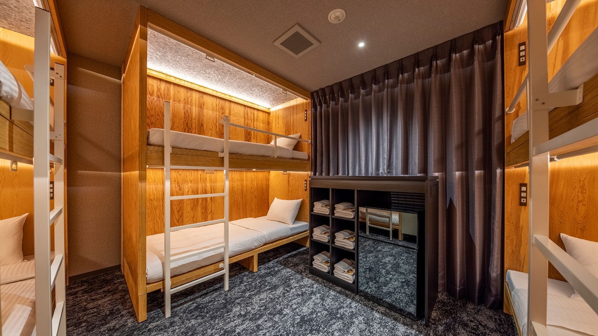 A bunk bed room with a built-in wardrobe and a small seating area.