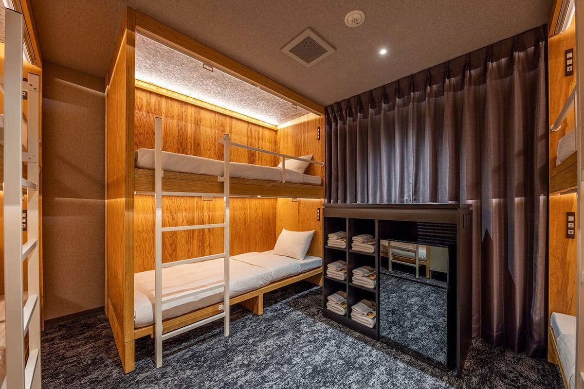 A bunk bed room with a built-in wardrobe and a small seating area.