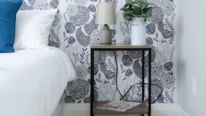 Une chambre à coucher avec un lit, une table de chevet avec une lampe, un magazine et une plante.