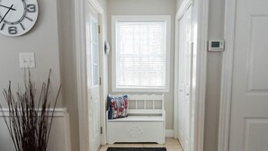 Un couloir avec un banc, une horloge et un thermostat.