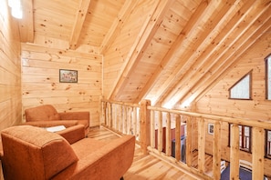 Una cabaña de madera con balcón, paredes de madera y un cuadro en la pared.