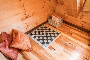 Un interior de madera con un tapete a cuadros, almohadas y una cesta de objetos.
