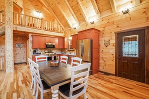 Una cabaña de madera con comedor, cocina y una puerta grande de madera.