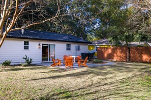 A white house with a dark roof, a wooden fence, and orange outdoor furniture. - Cozy Home Near Folly Field Beach (Hilton Head Island)
