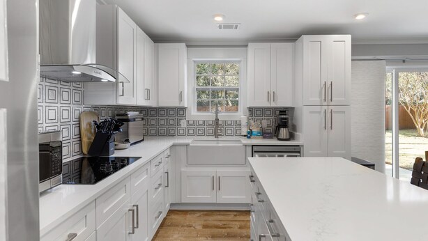 A modern kitchen with white cabinetry, a central island, and a window providing natural light.