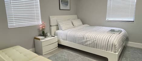 A bedroom with a bed, bedside tables, a bench, and patterned rugs.
