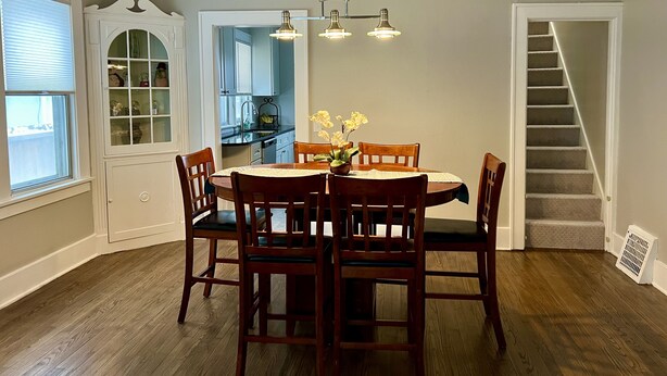 A dining area with a round table, wooden chairs, and a chandelier. - Downtown Home Away from Home 3BR/3BA (Rochester)