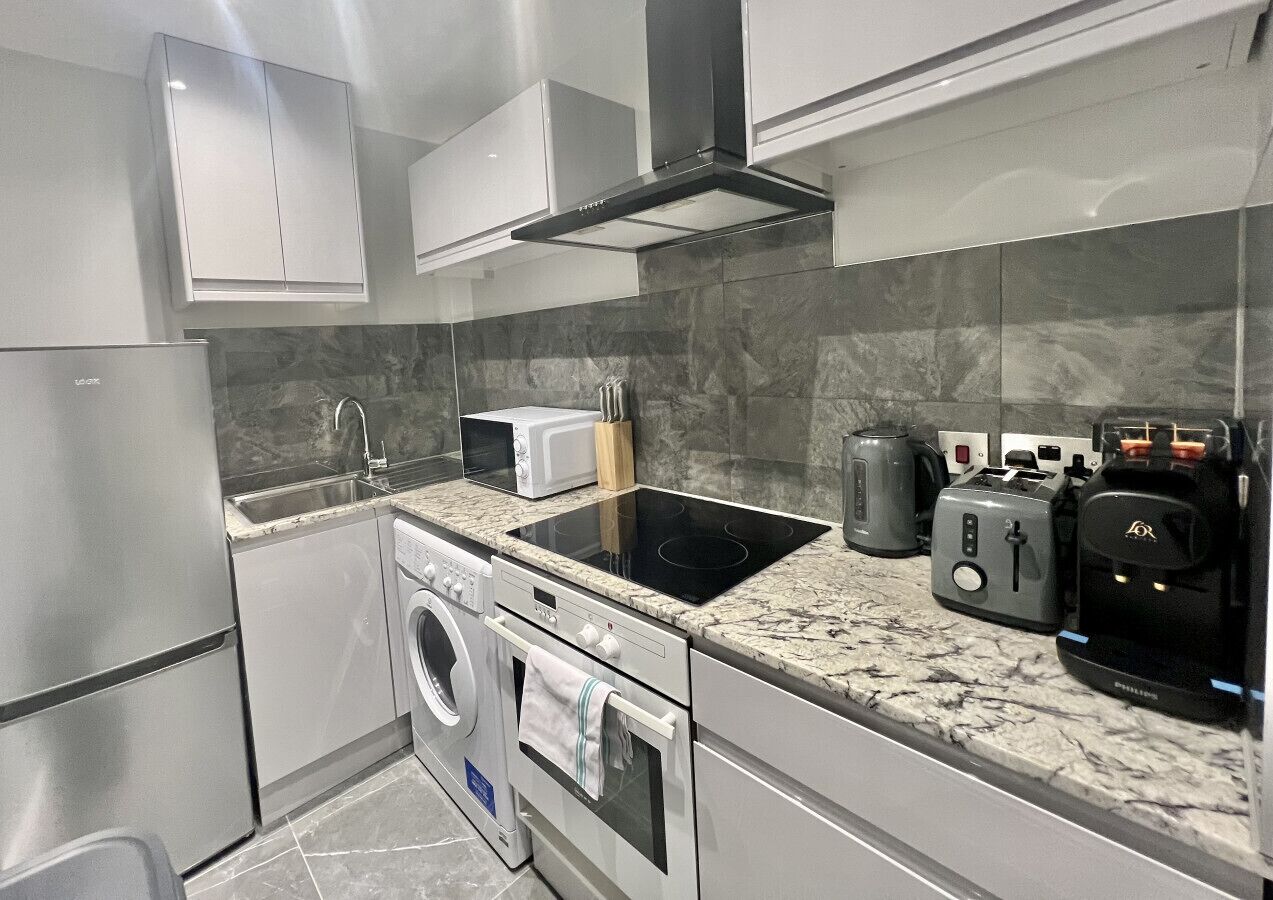 Een moderne keuken met roestvrijstalen apparatuur, een inbouwoven, magnetron en koffiezetapparaat.
