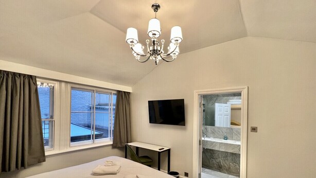 Ein Hotelzimmer mit einem großen Bett, einem Schreibtisch, einem Fernseher und einem Balkon mit Aussicht.