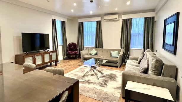 Ein modernes Wohnzimmer mit einer Couch, einem Glastisch, einem Fernseher und einem Essbereich.