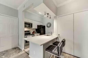 A modern kitchen with white cabinetry, a central island, and a built-in oven.