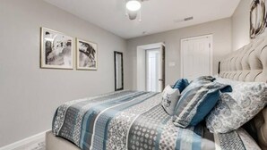 Un dormitorio con cama, ventilador de techo y dos cuadros en la pared.