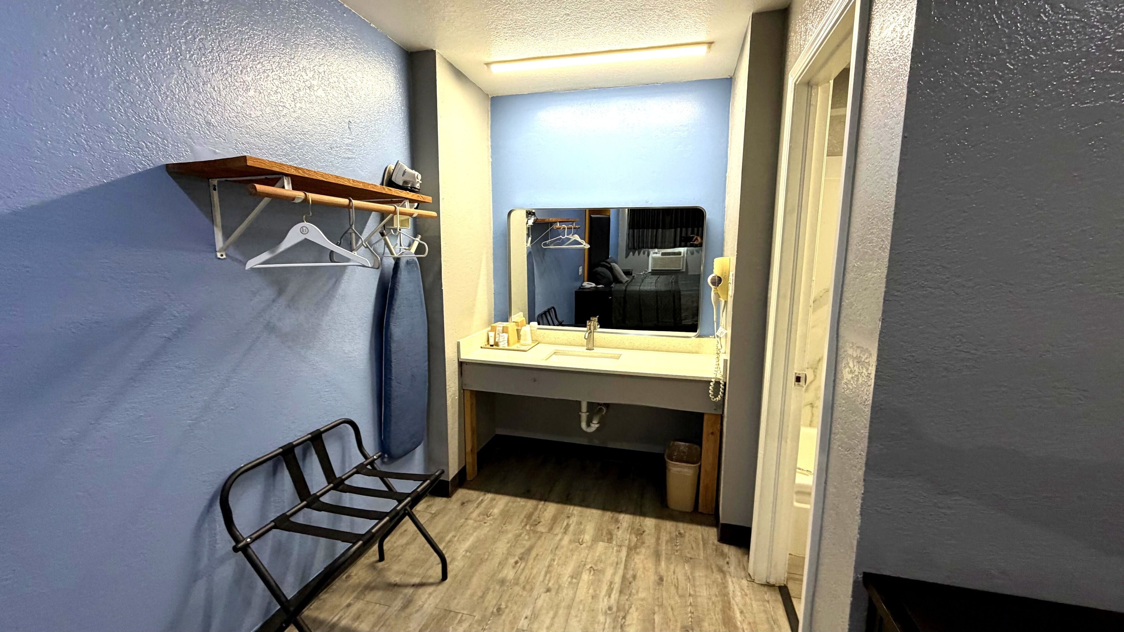 Un baño estrecho con espejo, lavamanos y toallero.