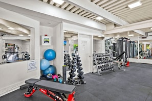 A gym with exercise equipment, a bench, and a wall-mounted emergency defibrillator.