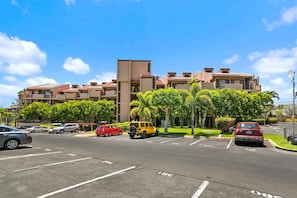 A multi-story hotel with a parking lot in front. - 2BR Kihei Unit with 2 Baths, 3-Zone Split AC, In-Unit Laundry, Pool and Hot Tub! (Kihei)