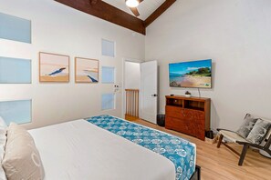 Een slaapkamer met een bed, een televisie, een kaptafel en kunst aan de muren.
