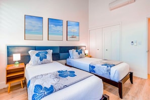A hotel room with two beds, a nightstand with a lamp, and a door with a lock.