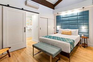 Un dormitorio con cama, banco, mesita de noche y cabecero.