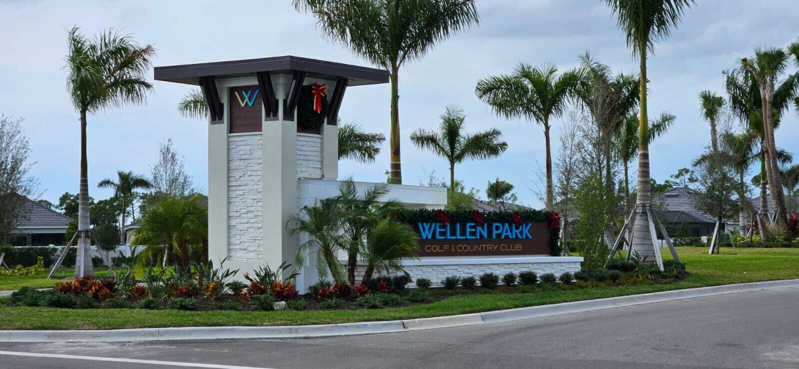 A sign for Wellen Park Golf & Country Club with a modern design, surrounded by palm trees and well-maintained landscaping.
