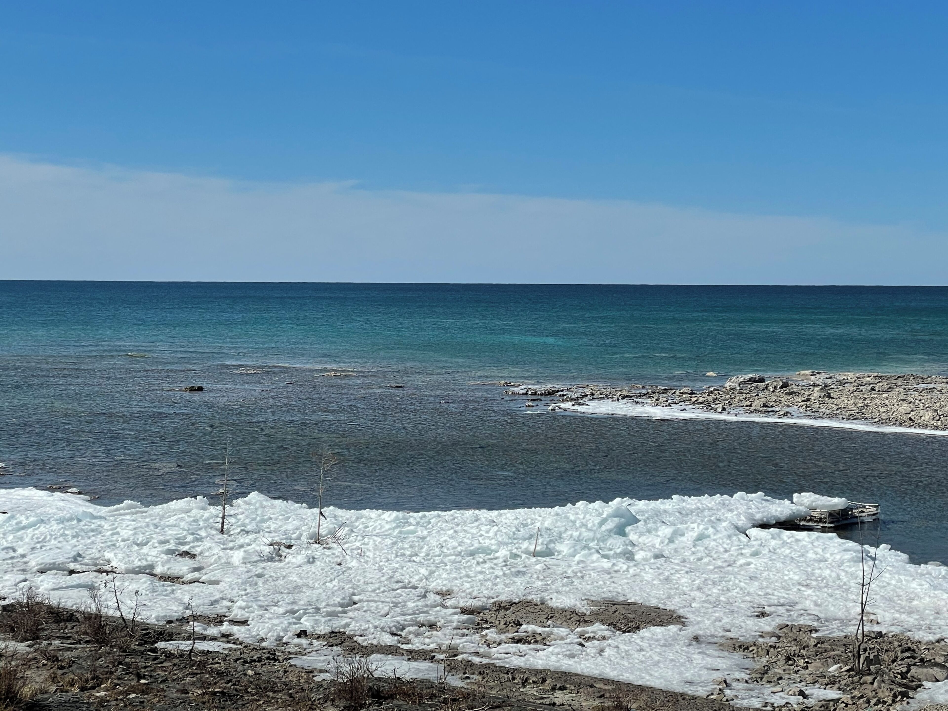 Eine felsige Küste mit klarem, blauem Wasser und Eisformationen.