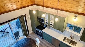 Uma cozinha moderna com vigas de madeira no teto, uma área de jantar com mesa redonda e vista para o deck externo.