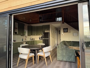A modern kitchen with green cabinets, a dining table with chairs, and a staircase leading to an upper level.