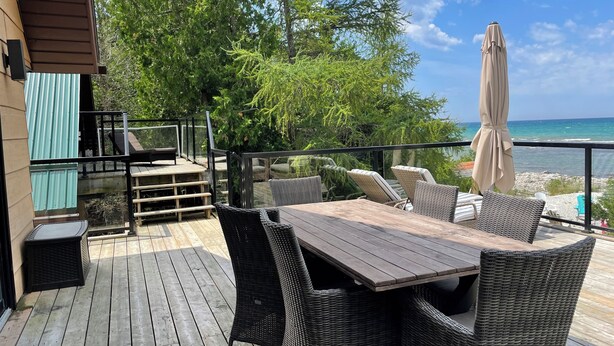 Um deck de madeira com móveis de vime, uma piscina e vista para o oceano.