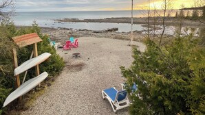 Uma praia de cascalho com um coreto, uma mesa e algumas cadeiras.