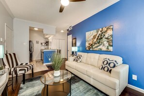 A living room with a sofa, a coffee table, and a blue accent wall. - I34 - Apt|Patio|11mi to Convention Ctr|Sleeps 2 (Irving)