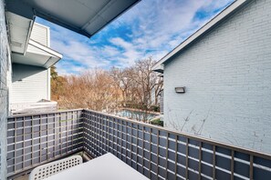 A balcony with a view of a swimming pool and trees, a white table, and a grey fence. - I34 - Apt|Patio|11mi to Convention Ctr|Sleeps 2 (Irving)