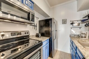 A modern kitchen with stainless steel appliances, a microwave, a toaster, and a refrigerator. - I34 - Apt|Patio|11mi to Convention Ctr|Sleeps 2 (Irving)