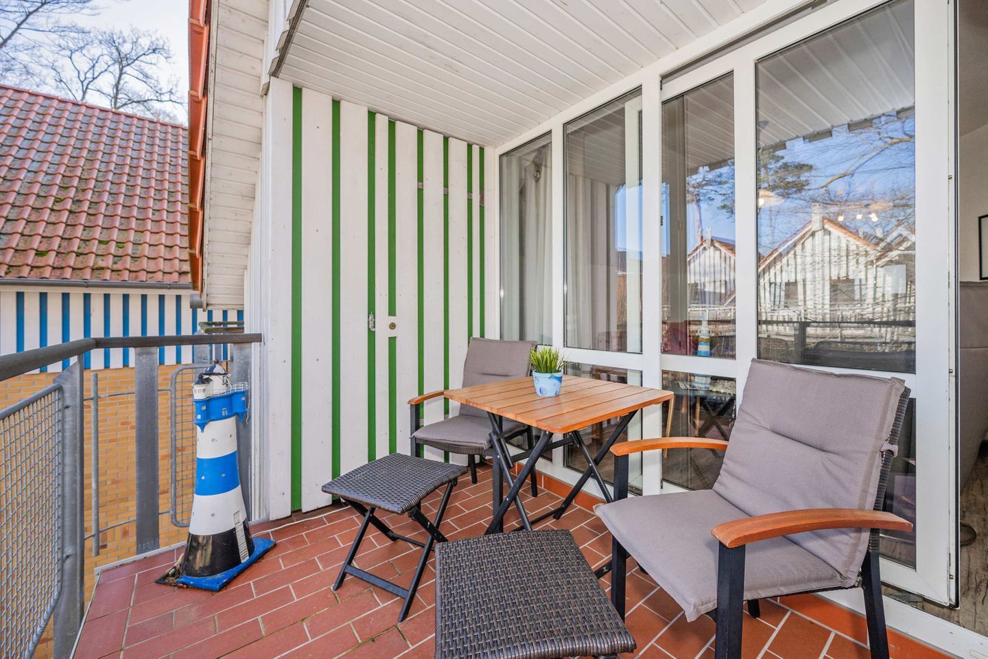 A balcony with a table and chairs, a potted plant, and a lighthouse model.