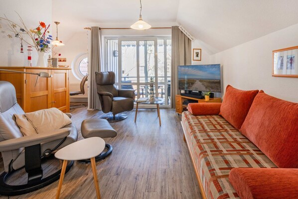 Ein Wohnzimmer mit einer Couch, einem Sessel und einem Fernseher.
