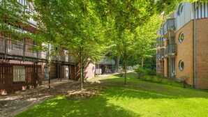 Ein Innenhof mit Baumallee, Ziegelgebäuden und einer Rasenfläche.