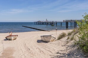 Une plage avec deux bateaux, une jetée et un ciel dégagé.