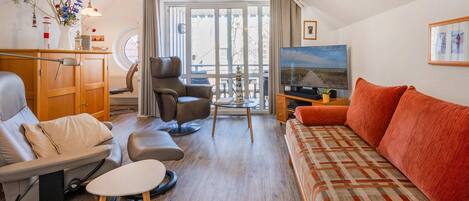 Un salon avec un canapé, un fauteuil et un téléviseur.