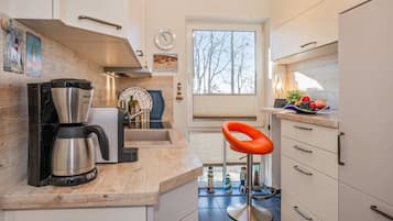 Eine moderne Küche mit Kaffeemaschine, Spüle und einem Fenster mit Blick auf Bäume.