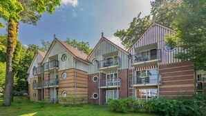 Ein mehrstöckiges Wohngebäude mit Balkonen, einer Ziegel-Fassade und einer umlaufenden Grünfläche.