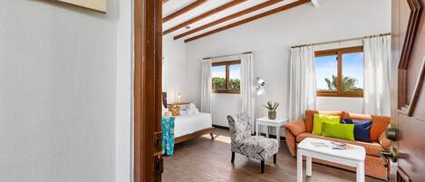 A room with a bed, a sofa, a chair, and a small table. There is a sign on the wall that reads "Bista."