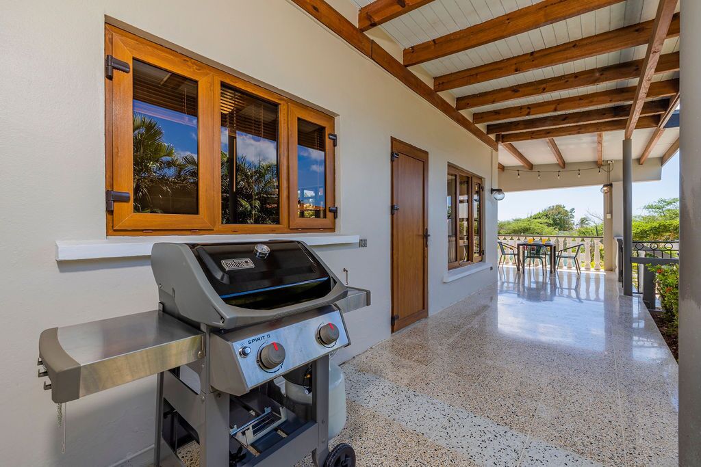 A covered patio with a barbecue grill, a wooden ceiling, and a view of the outdoors.