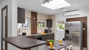 Una cocina moderna con una isla central, electrodomésticos de acero inoxidable y un ventanal que proporciona luz natural.