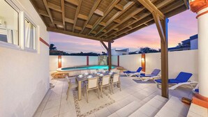 Un patio al aire libre con piscina, sillas de descanso y una mesa de comedor para seis personas.