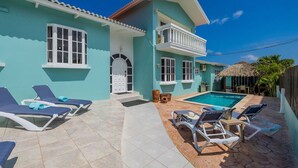 A two-story house with a swimming pool, outdoor seating, and a thatched roof structure. - ~Sleeps 12 ~Spacious ~Private Pool ~Great Location (Noord)