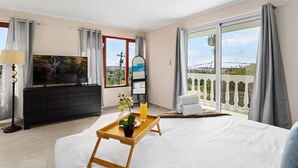 A hotel room with a bed, a TV, a balcony with a view, and a tray with a drink and a plant. - ~Sleeps 12 ~Spacious ~Private Pool ~Great Location (Noord)