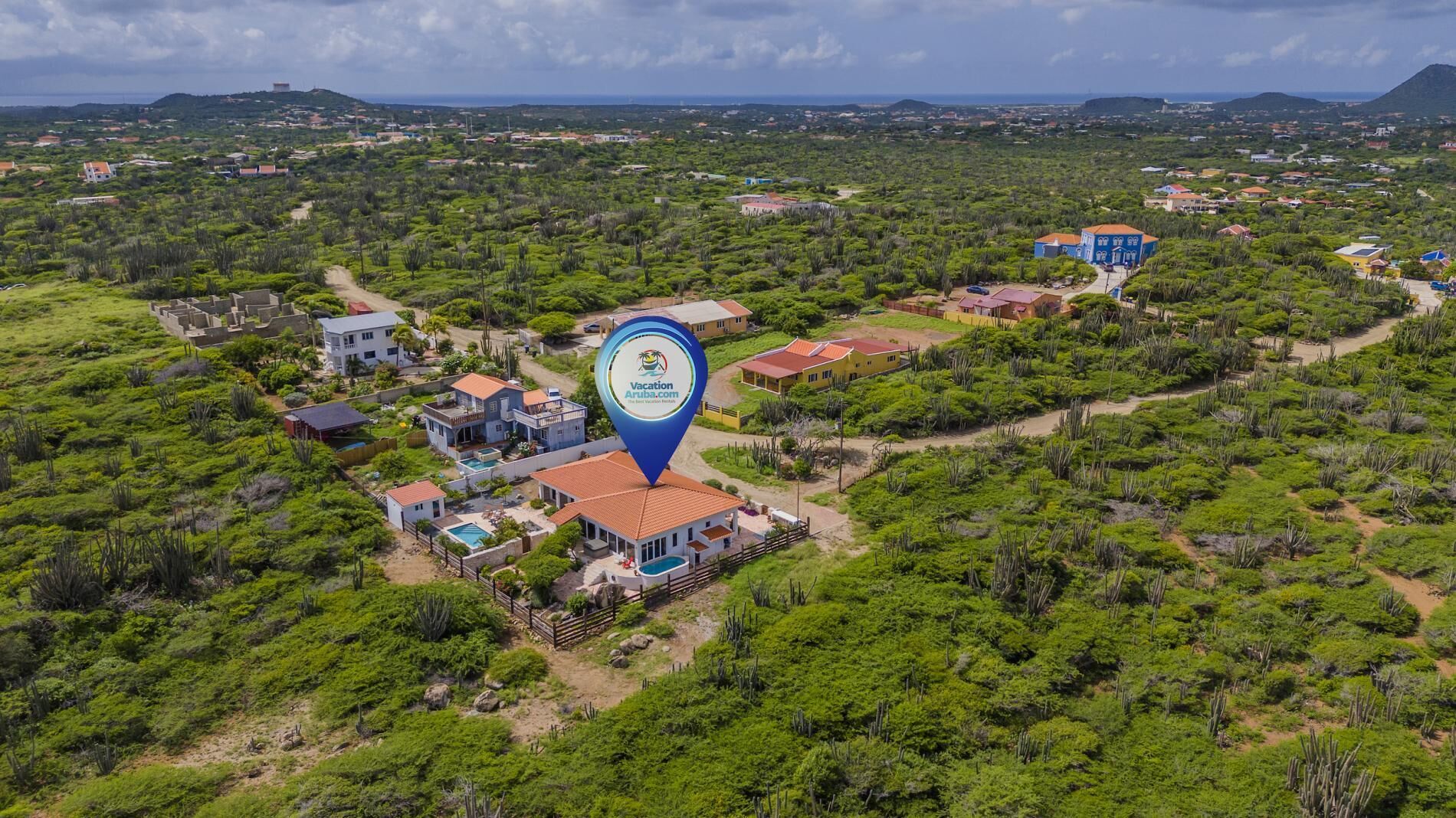 Vista aérea de un resort con varias construcciones, una piscina y un paisaje verde exuberante.