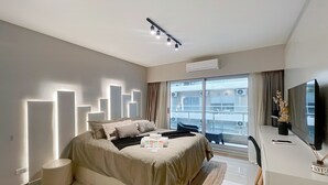Een moderne hotelkamer met een groot bed, een bureau met televisie, en een balkon met uitzicht op de stad.