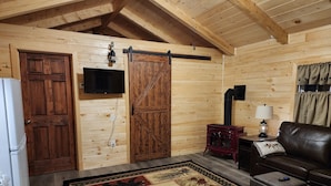 Un interior de cabaña acogedor, con paredes de madera, una chimenea, un sofá y una alfombra.