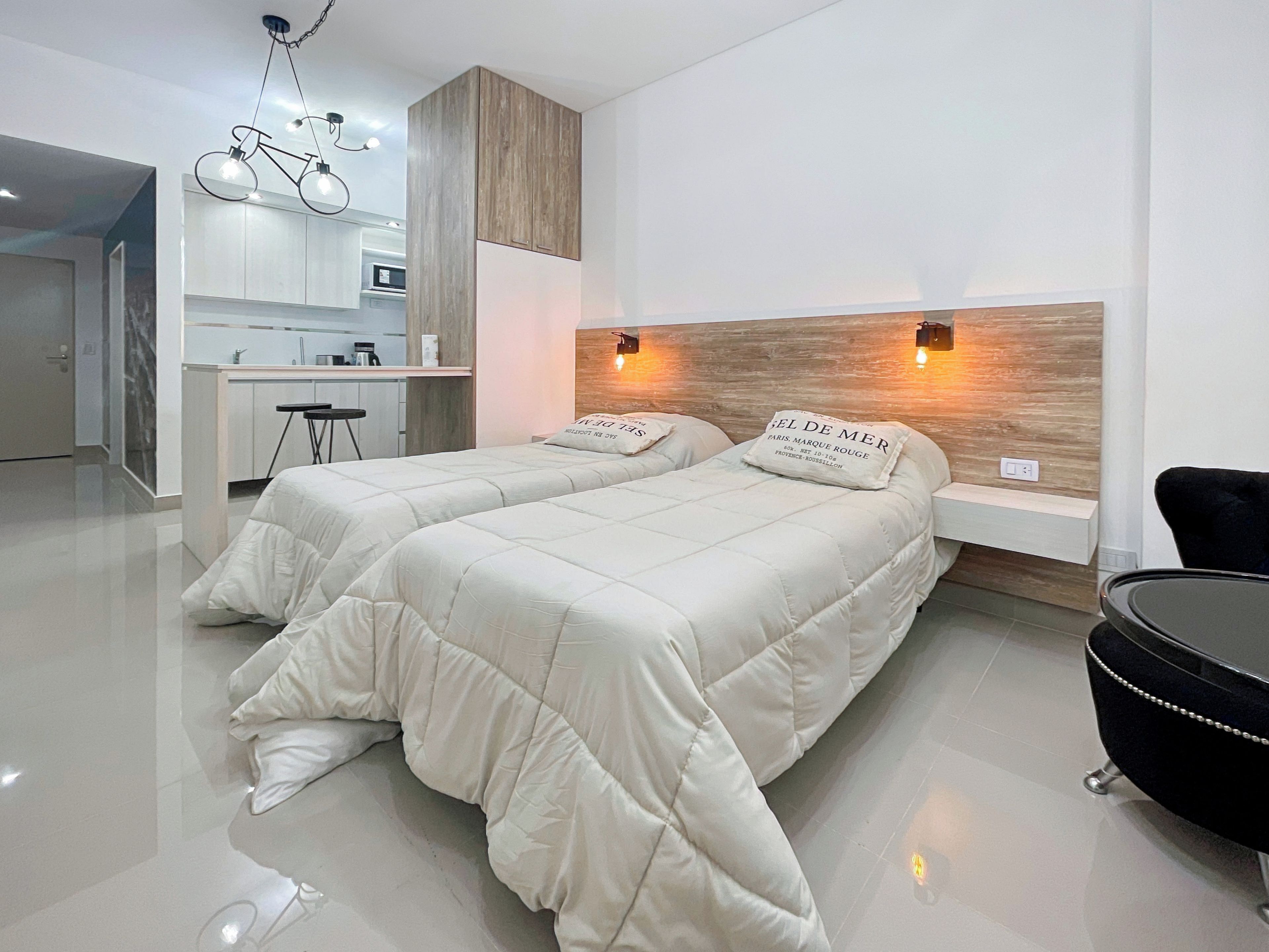 A modern hotel room with two beds, a desk, and a chair.