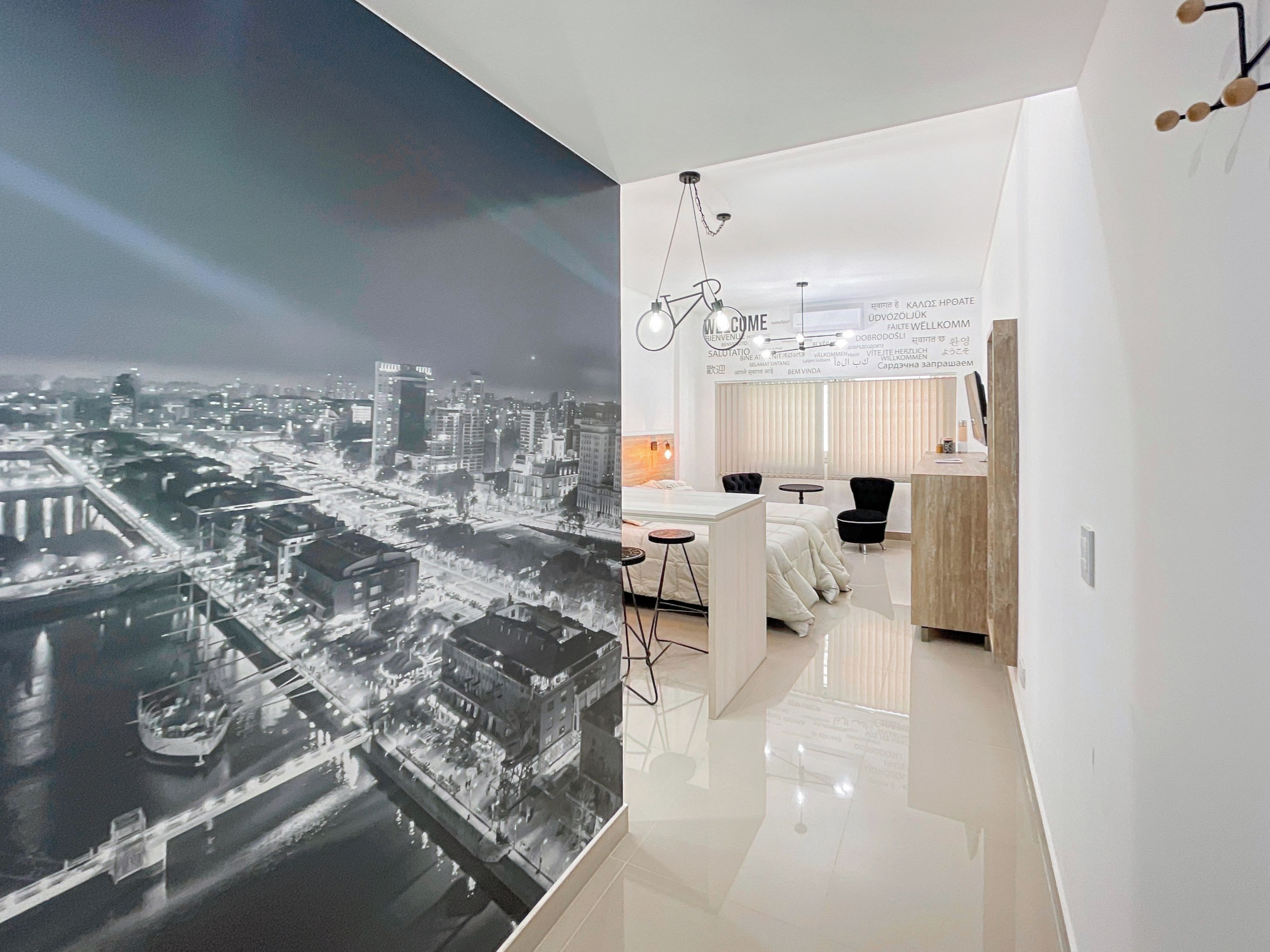 Habitación de hotel moderna con vistas a un paisaje urbano, una cama, un escritorio y una silla.